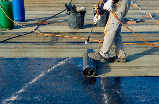 A person using a spray object to clean a roof