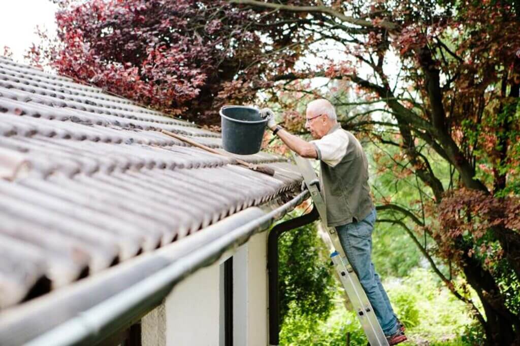 A man cleans the roof of a house in South Florida, ensuring its maintenance and safety.